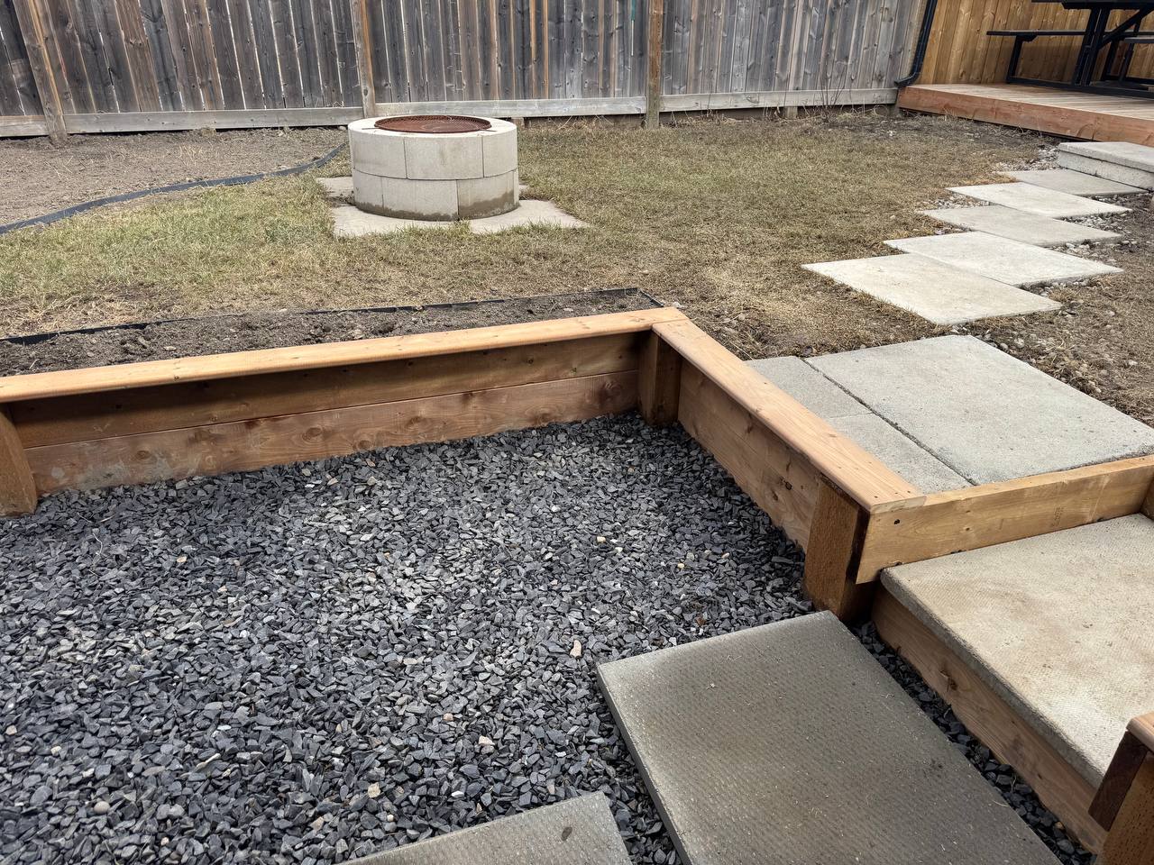 Raised garden bed construction with gravel fill and stepping stone installation in progress