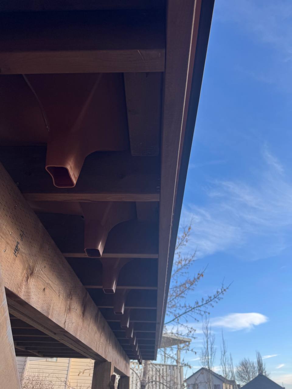 Completed metal beam overhang structure with decorative brackets attached to brick building