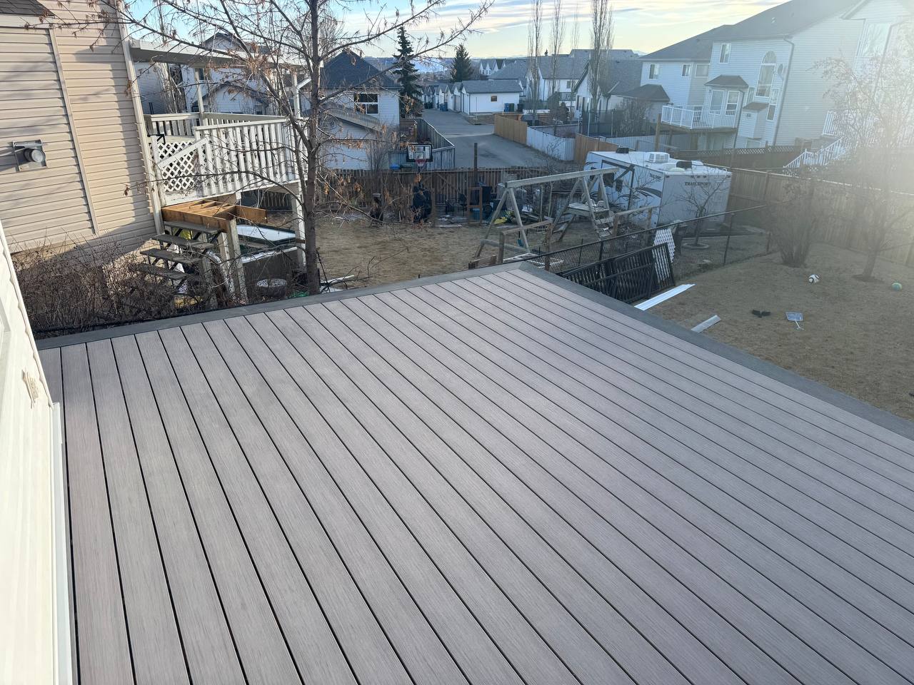 Newly installed composite deck with clean finished surface overlooking residential backyard