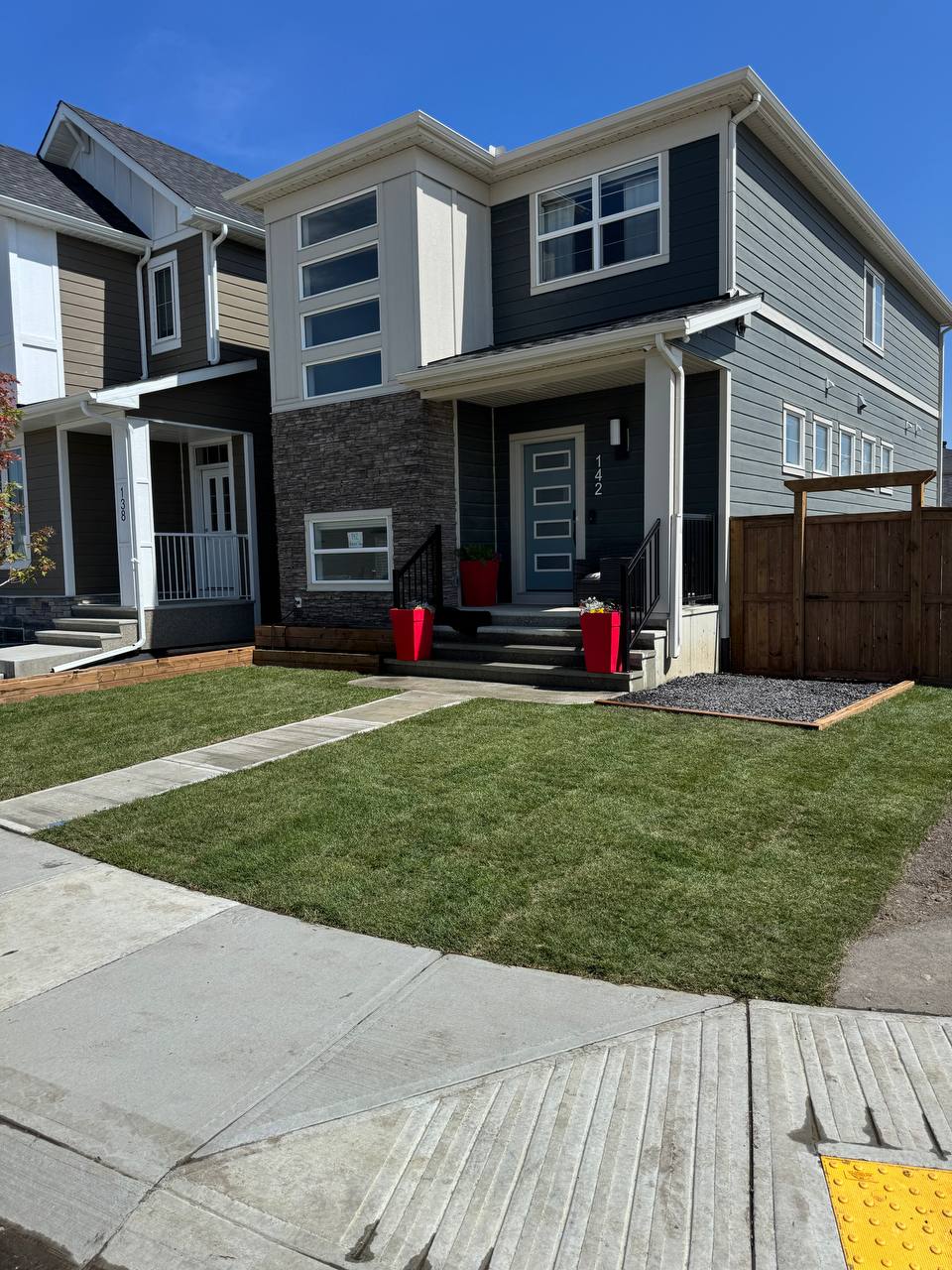 Modern residential front yard with concrete walkway, sod installation, and gravel landscaping