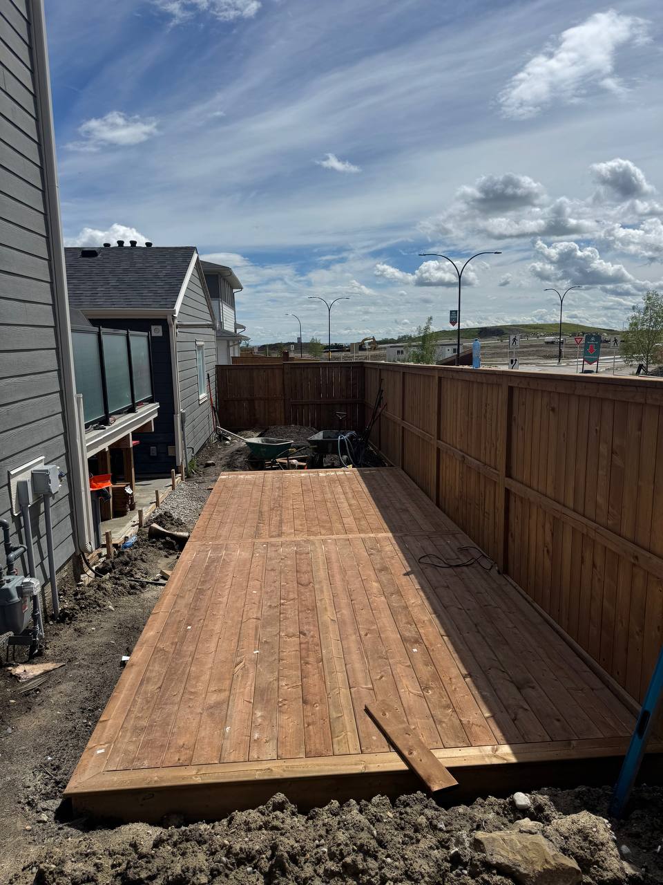 Wooden deck construction in progress with framing completed and staining underway in residential bac