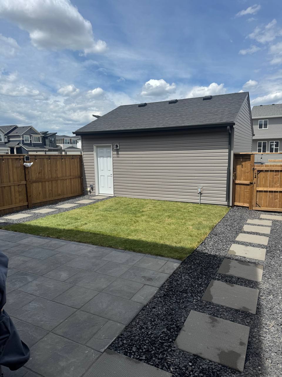 Completed backyard hardscape with patio, stepping stones, gravel borders, new sod, and garage struct