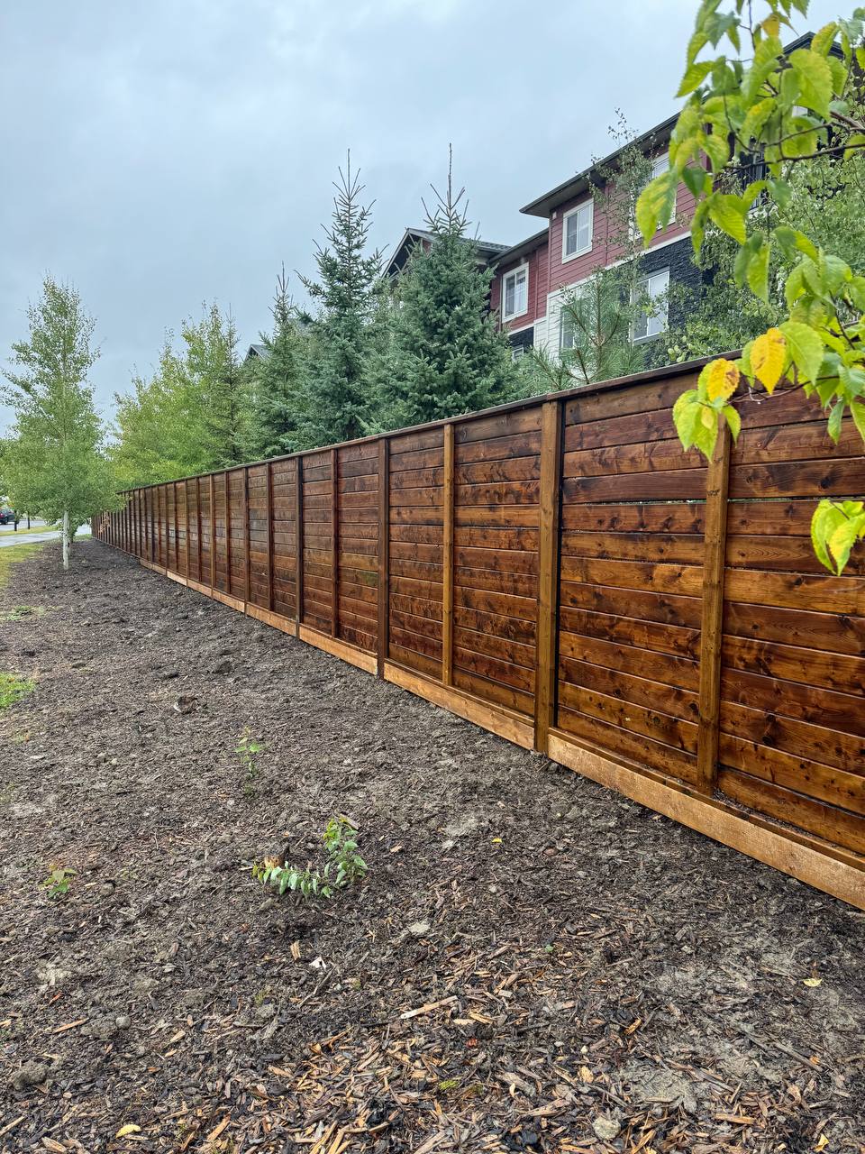 Newly installed horizontal wood fence with metal frame posts along residential property