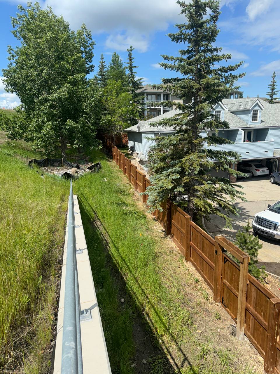 Completed concrete retaining wall with drainage system along residential property line