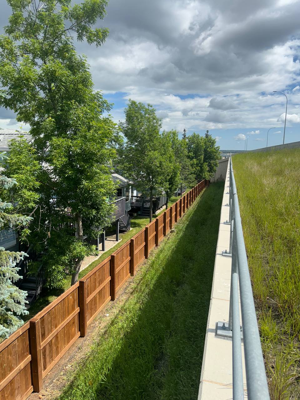 Completed concrete retaining wall with adjacent wooden fence in residential neighborhood