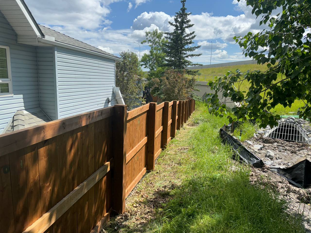 Wood fence installation in progress along residential property with staging area visible