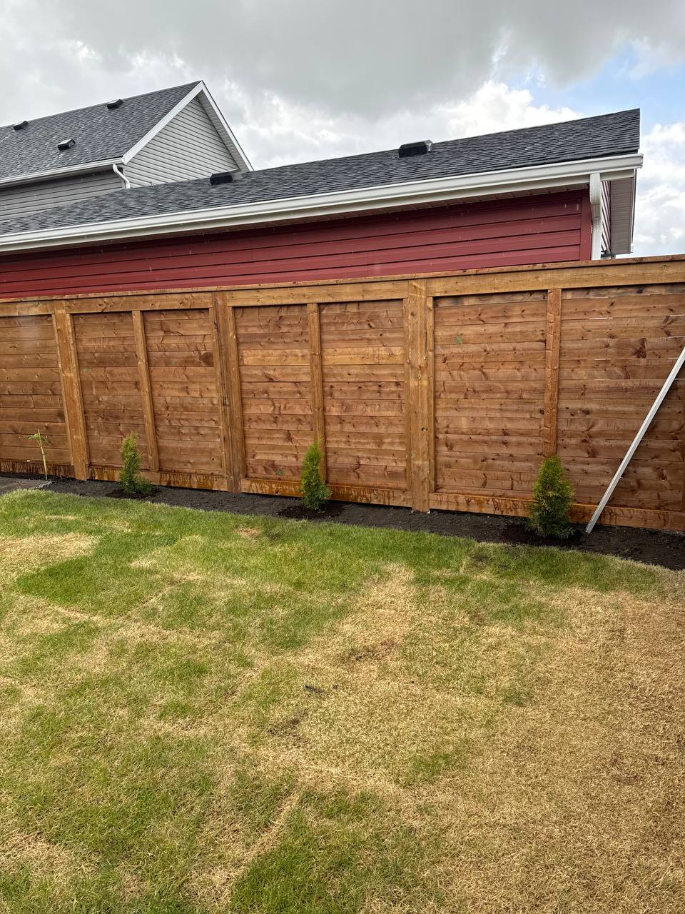 Newly installed horizontal wooden privacy fence with framed panels along residential property