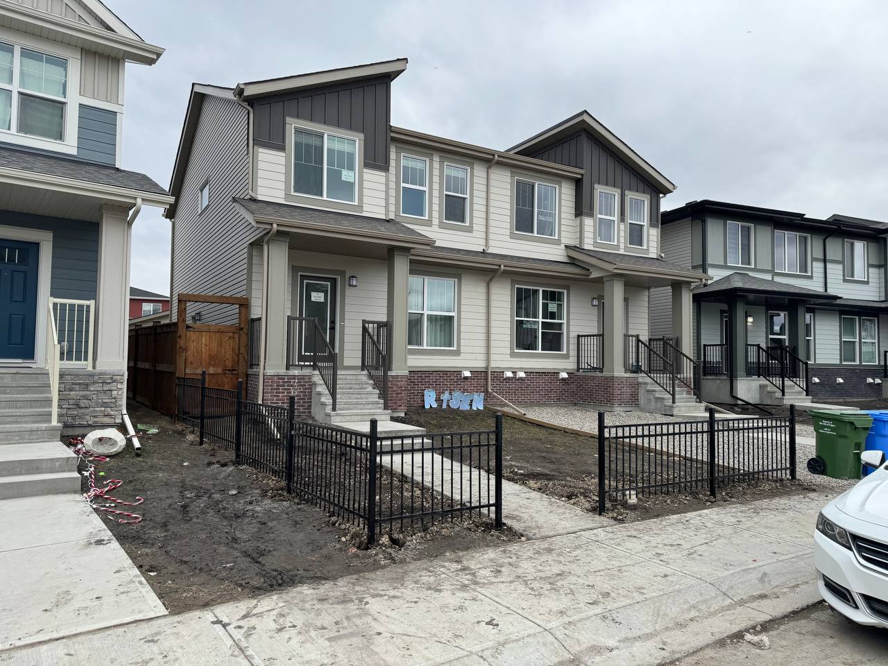 New residential property with black metal fencing and concrete patio under construction, landscaping