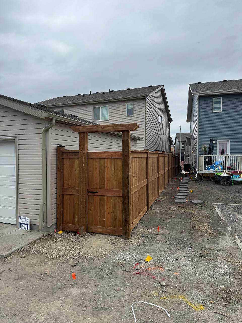 Wood fence construction in progress with pergola structure and layout markers visible in residential