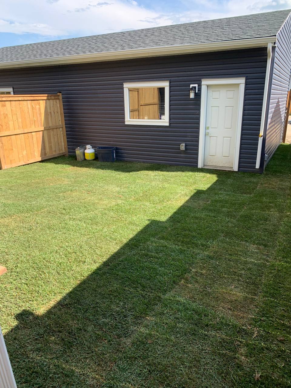 Newly installed sod lawn with clean edges around residential garage structure
