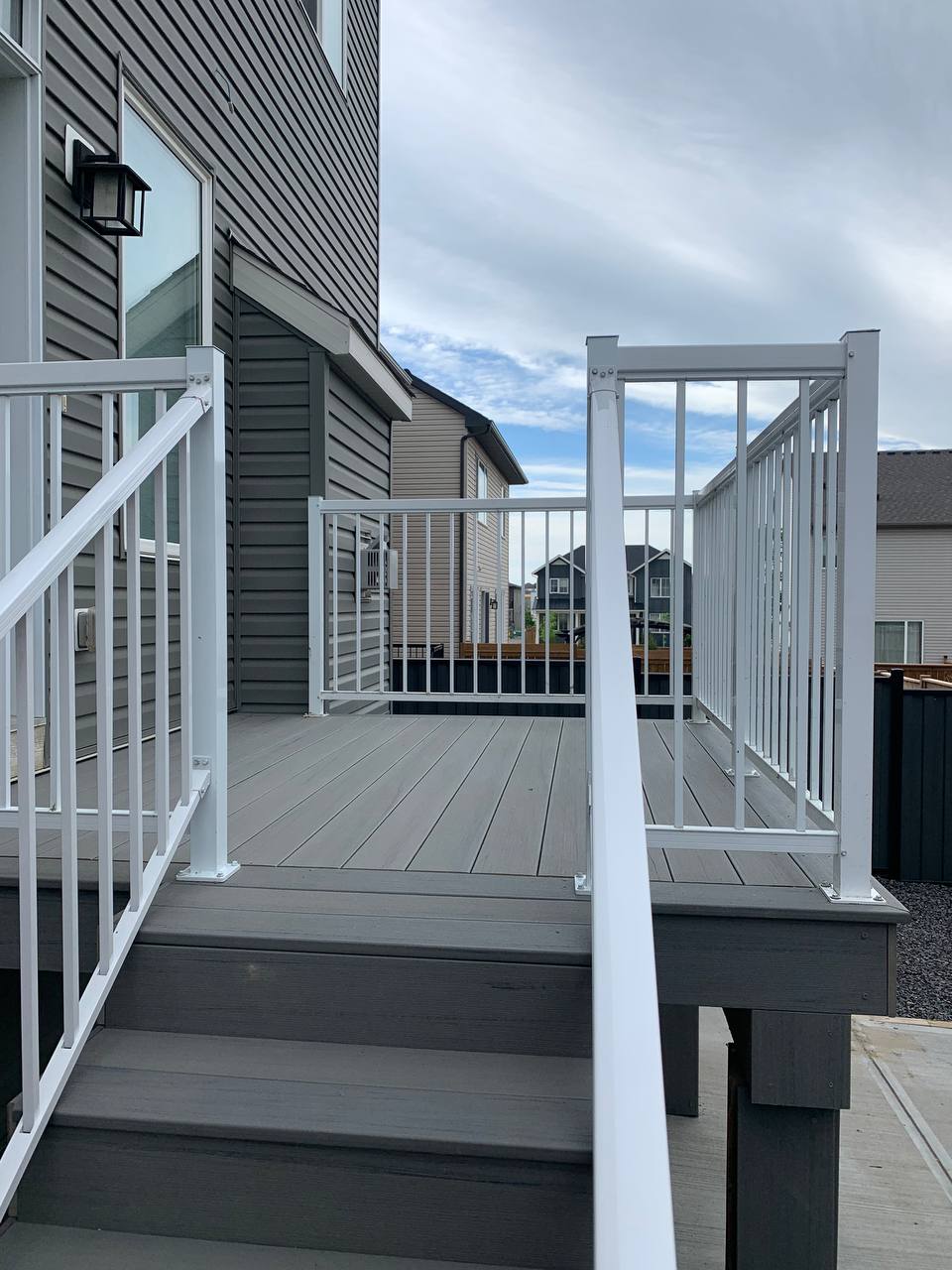 Newly constructed elevated composite deck with white railings and multiple levels overlooking reside