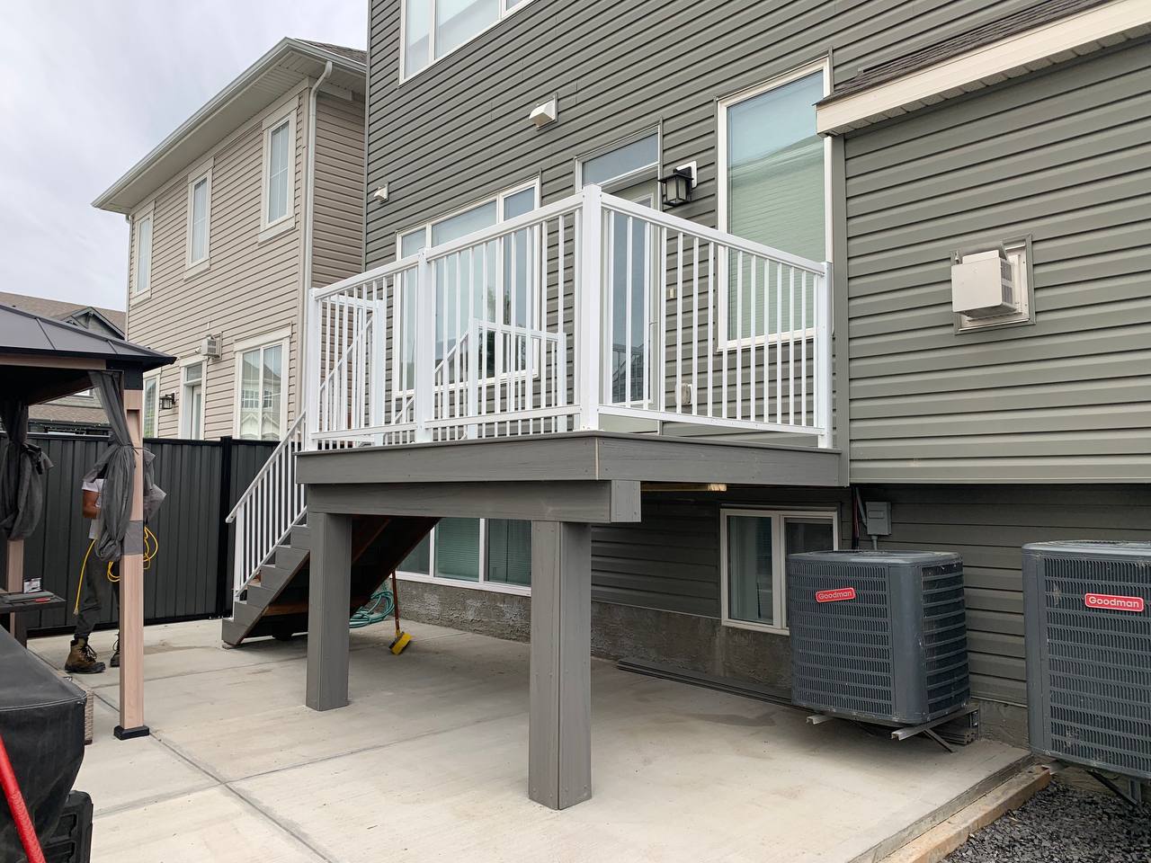 Elevated white railed deck with concrete under-deck space and HVAC units installed