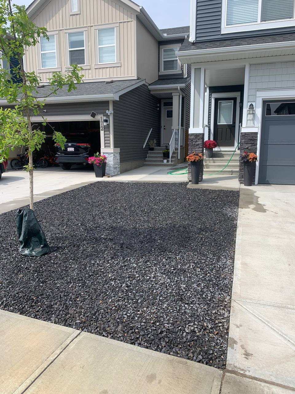 Gravel landscaping installation in progress with protective fabric and edging in front yard