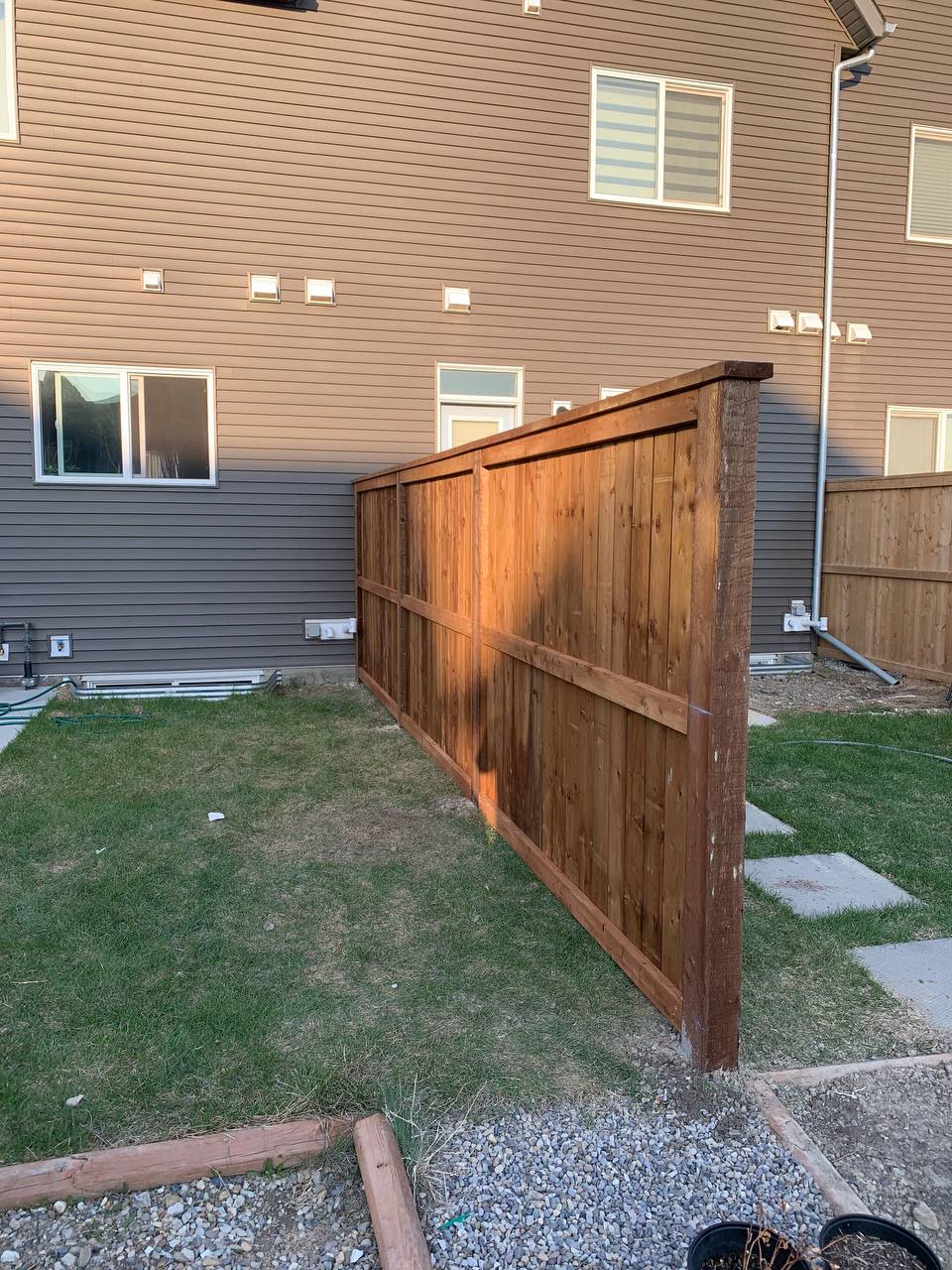 Newly installed wooden privacy fence with horizontal rails in residential backyard