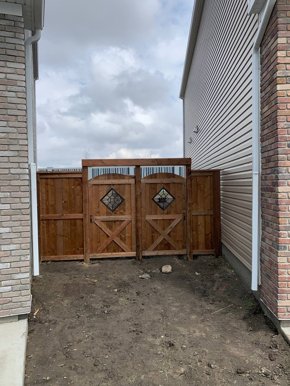 Custom wooden stable doors with diamond glass inserts installed in brick-lined passage