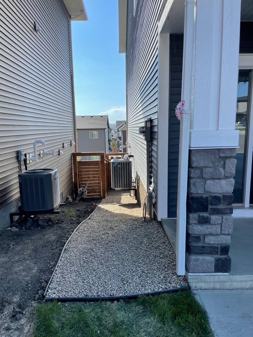 Completed gravel pathway between residential structures with edging and drainage solutions installed