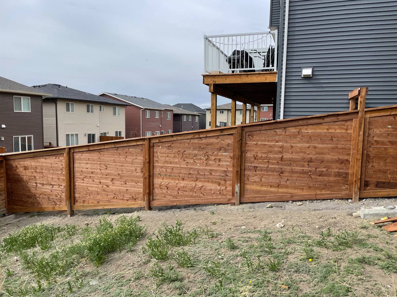 Newly installed horizontal wooden privacy fence with residential neighborhood backdrop