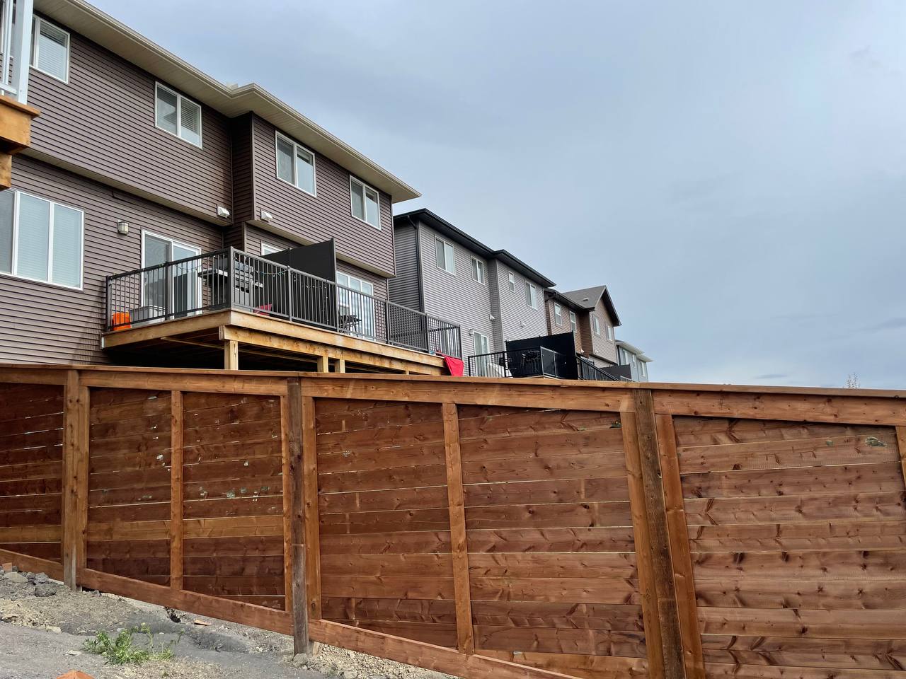 Completed wooden privacy fence installation with horizontal boards in front of residential townhouse