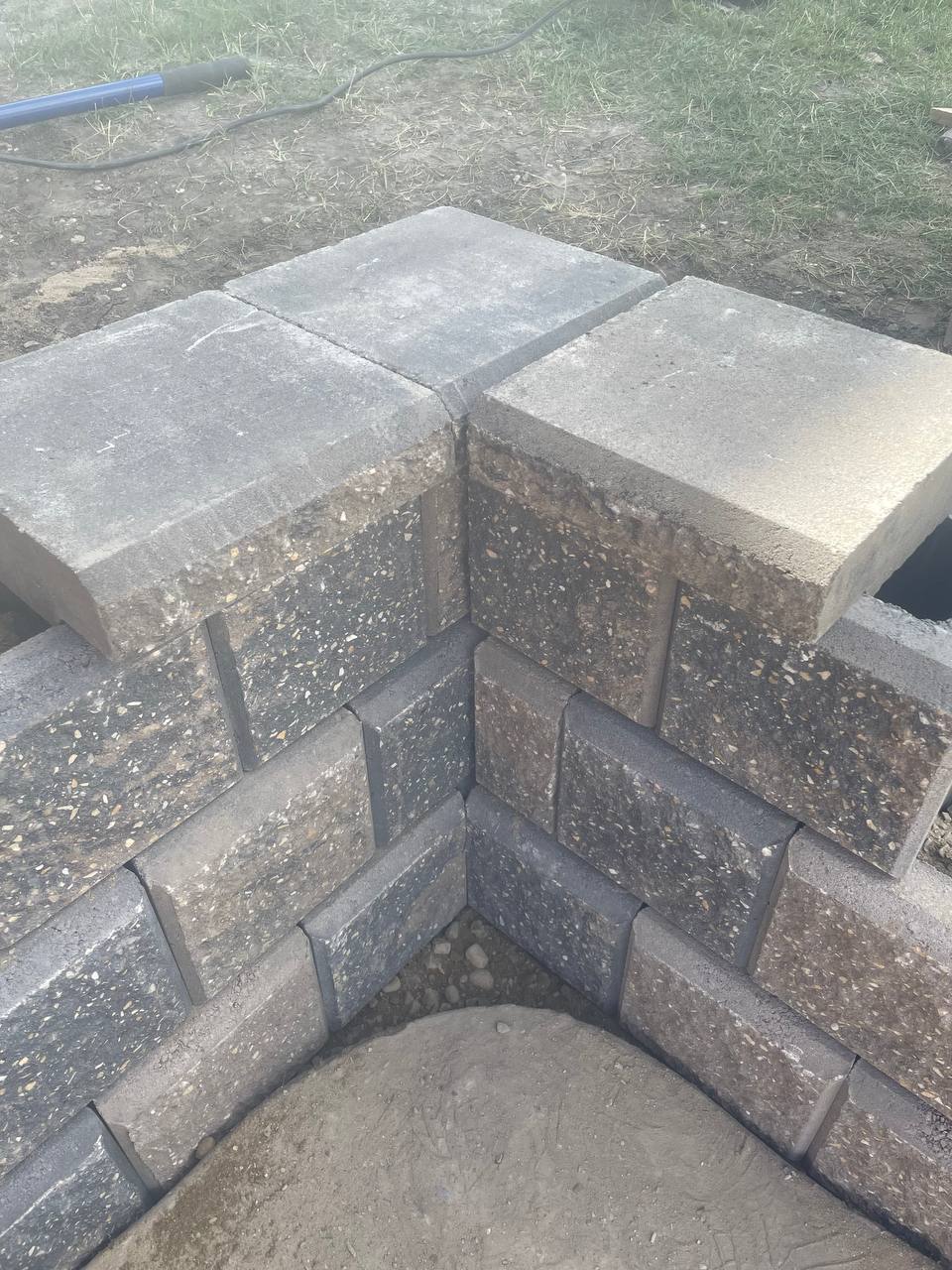 Concrete retaining wall construction in progress with stacked blocks and exposed interior