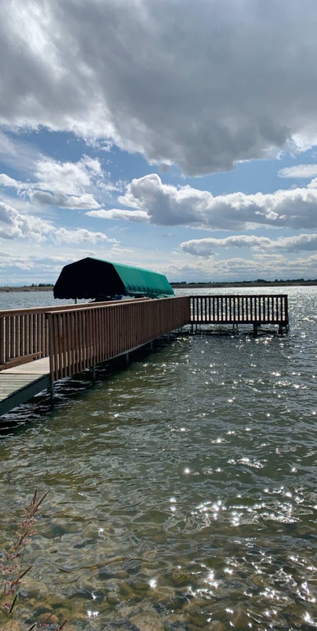 Waterfront deck with railings overlooking calm bay waters with covered boat storage