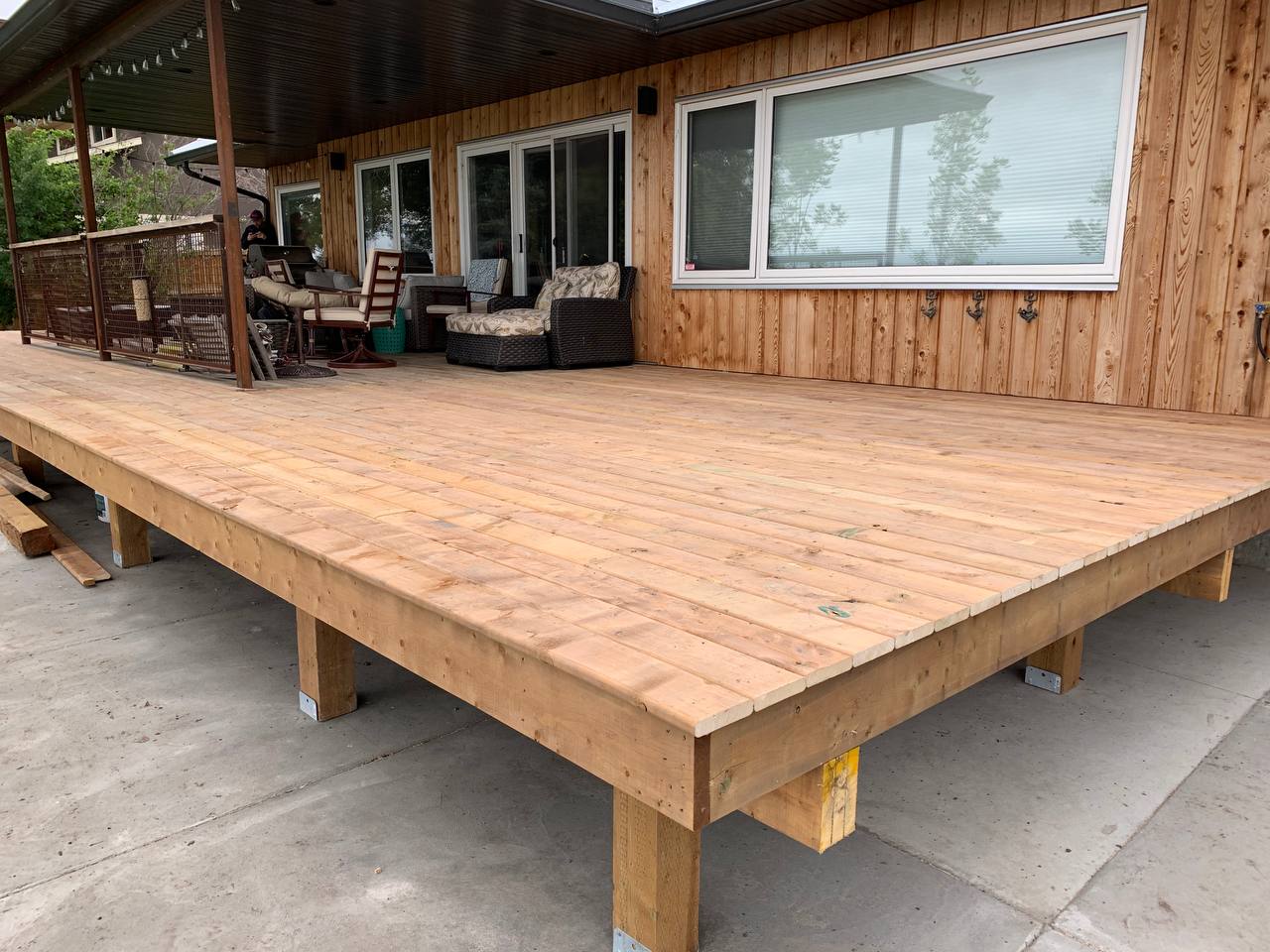 Newly constructed wooden deck with large platform attached to cabin-style home