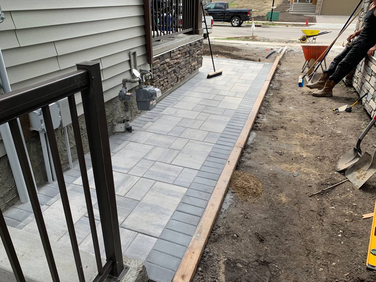 Patio installation in progress with pavers being laid and edging completed