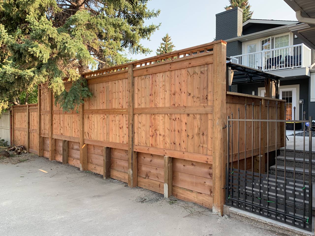 Completed cedar privacy fence with lattice top and black metal gate installation